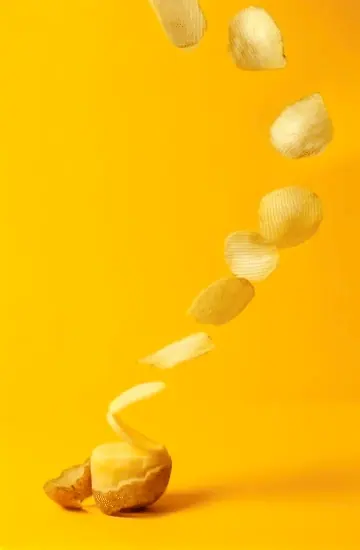 Potato chips falling against a yellow background
